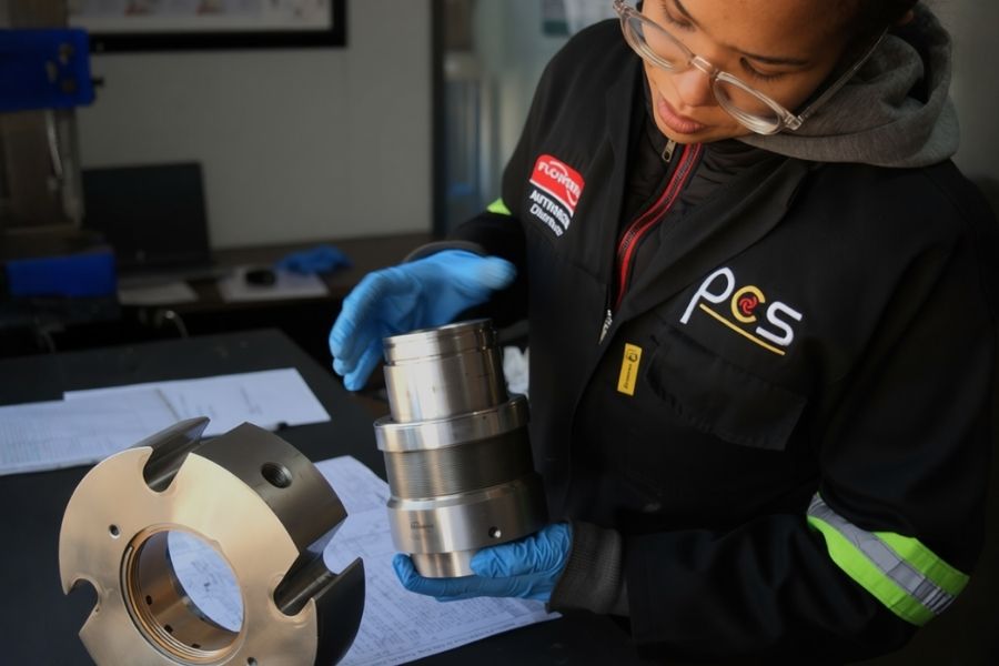 PCS technician inspecting a precision-machined mechanical seal component during quality control inspection, using documented measurement specifications in a controlled workshop environment.