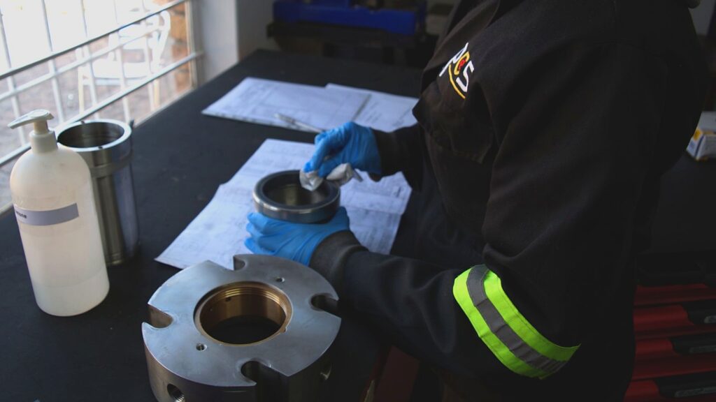 PCS technician inspecting and cleaning a mechanical seal component during the repair and failure assessment process.