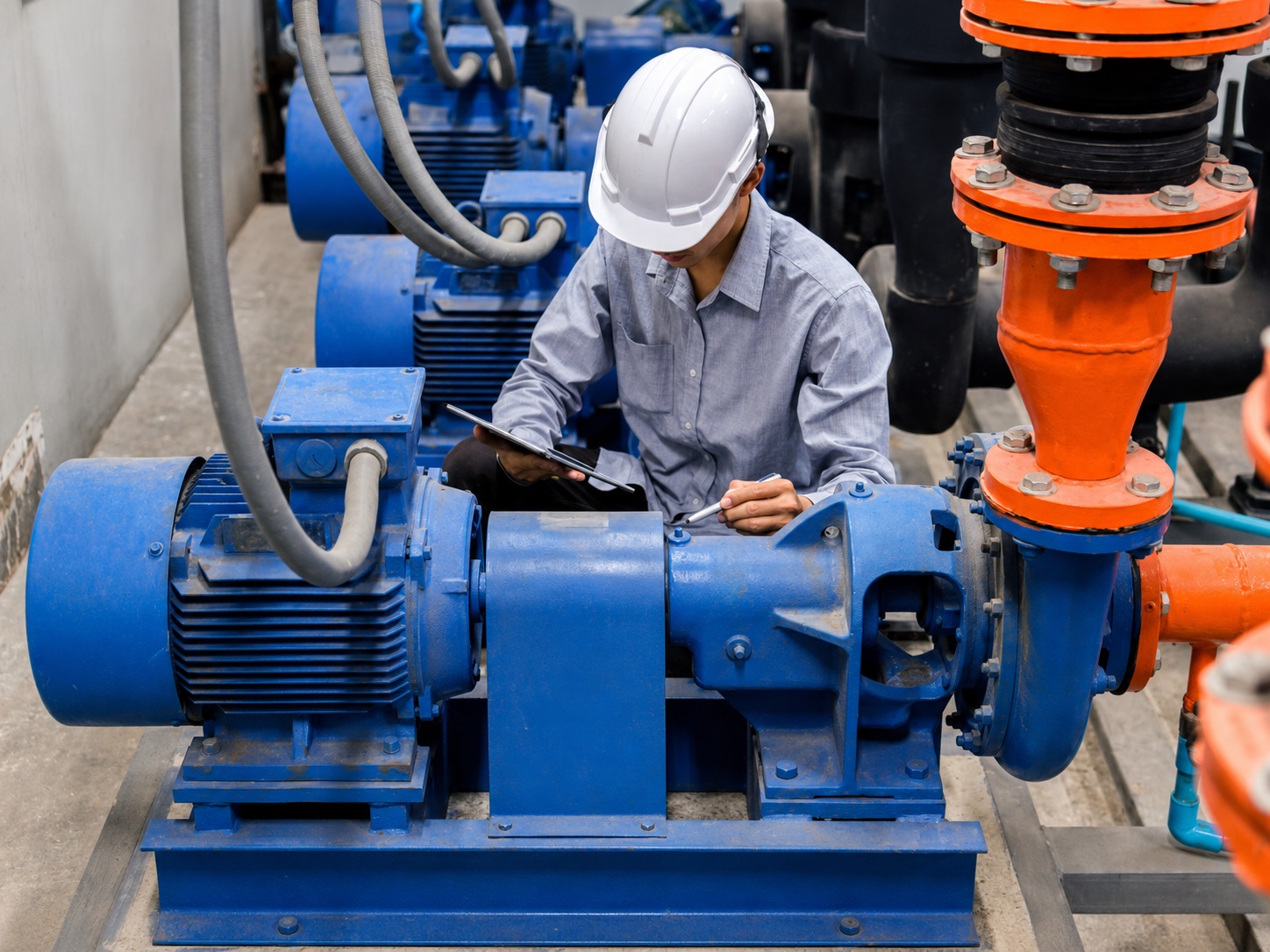 Technician inspecting an installed industrial pump during an equipment condition assessment.