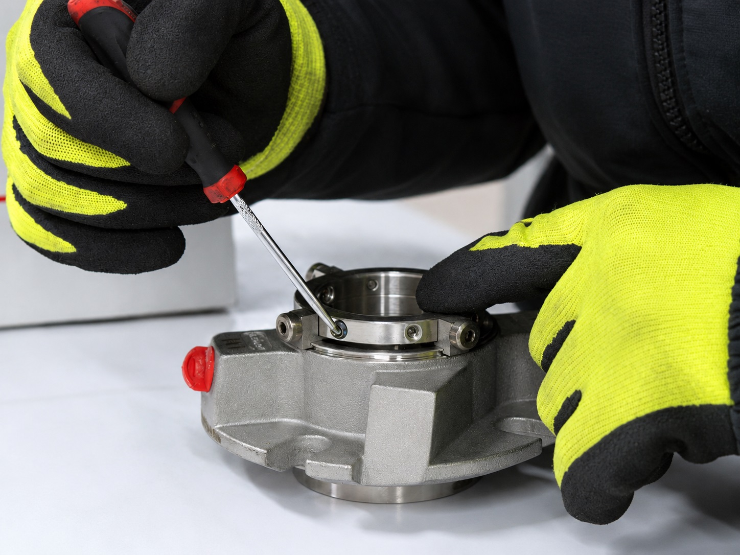 Technician wearing protective gloves working on a mechanical seal assembly during inspection and assembly.