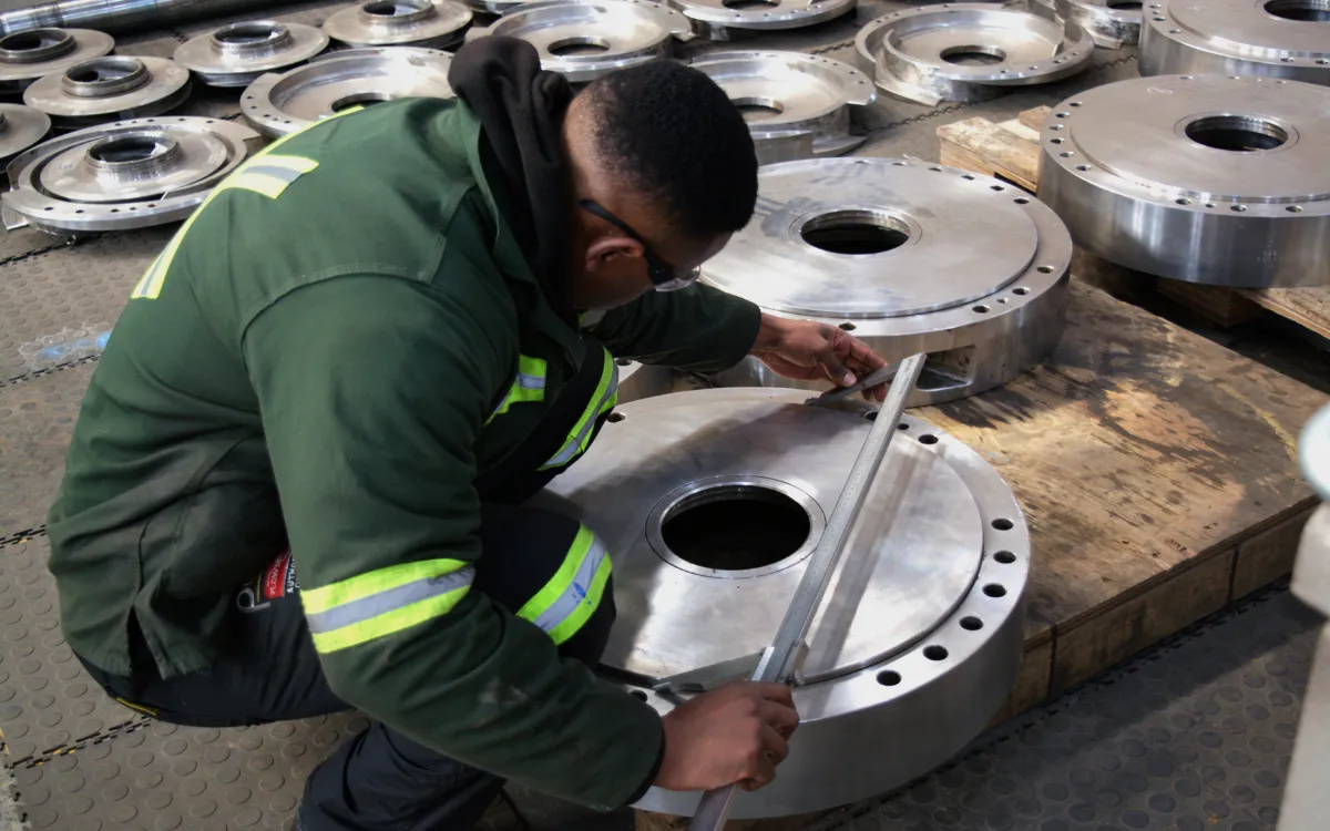 PCS technician measuring a machined industrial pump component during workshop inspection